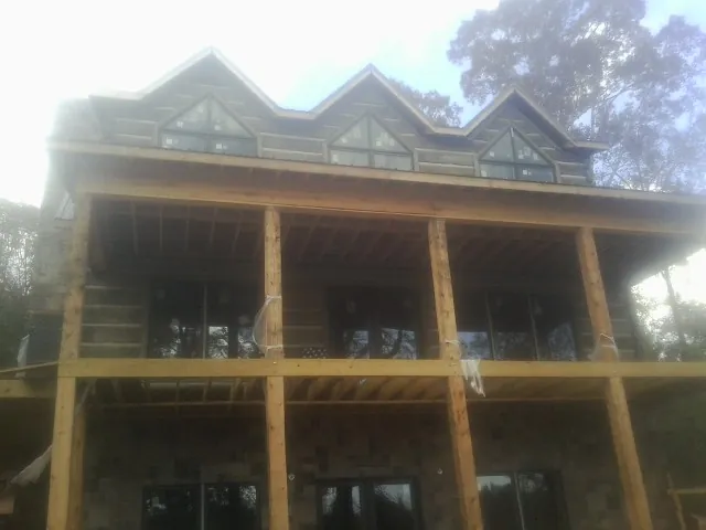 Dormers and porch framing on a large log home under construction — Roof Coating work by our crew in Enid