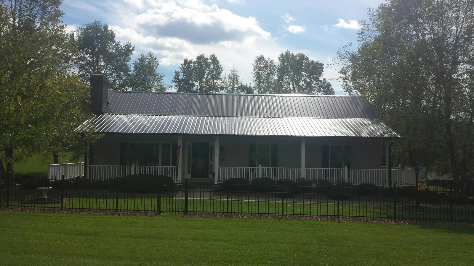 Gray metal roof on a brick ranch with a full width front porch — Gutter Guard Installation work by our crew in Enid