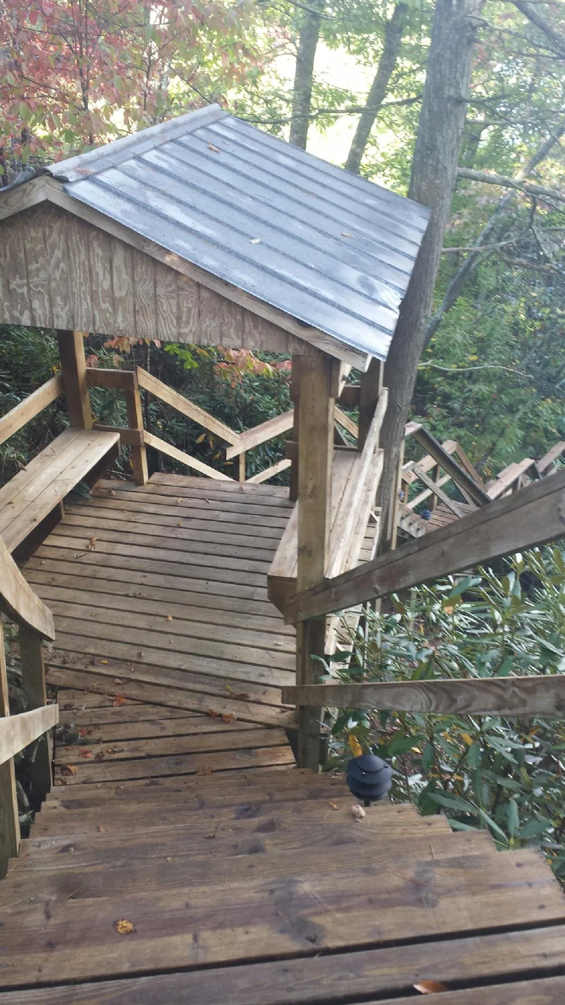 Metal roofed shelter over wooden steps on a wooded walkway — Skylight Repair & Installation work by our crew in Enid