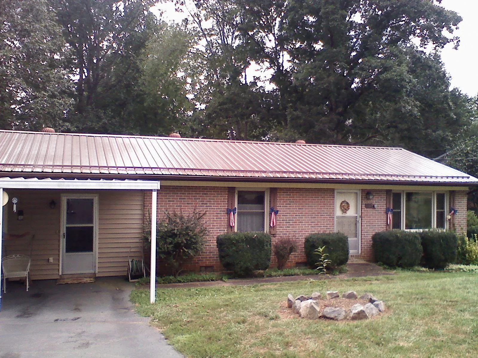 Bronze metal roof and carport on a brick ranch home — Roof Repair work by our crew in Enid