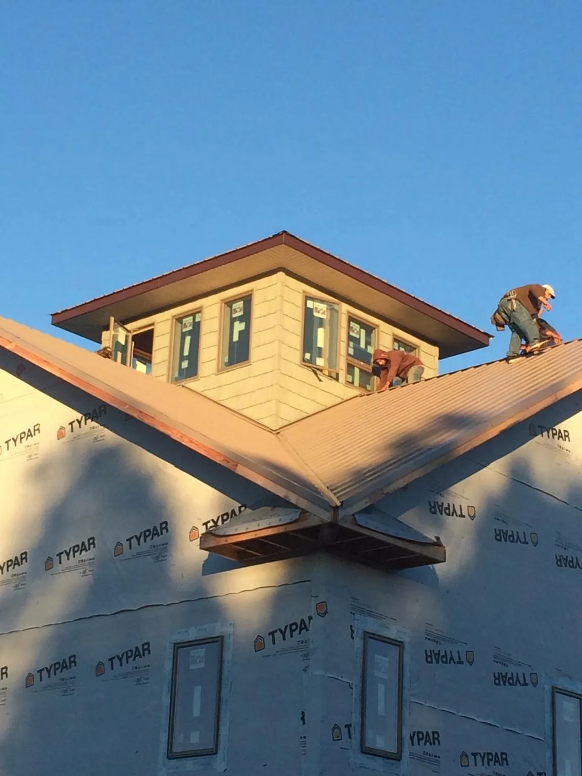 Roofers working around a rooftop cupola on a new metal roof at sunset — Roof Waterproofing in Enid by Roofing Brothers